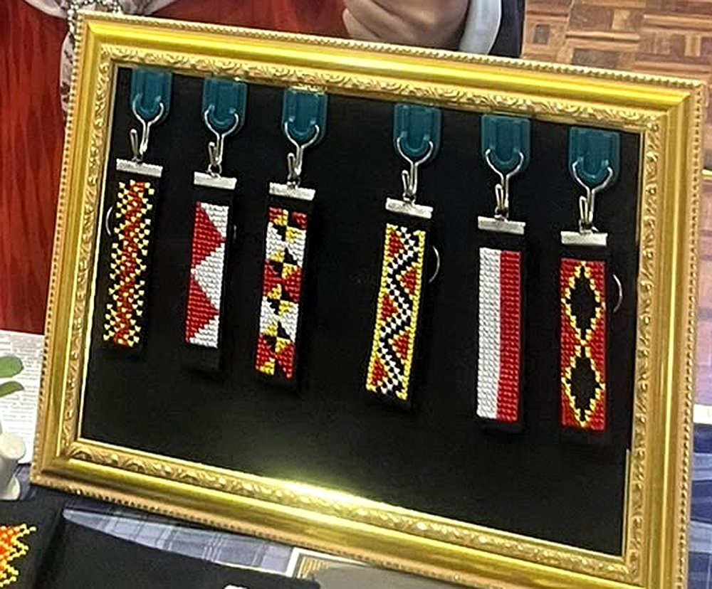 Bingkai emas displaying produk bergaya monogram dengan tali pelangi