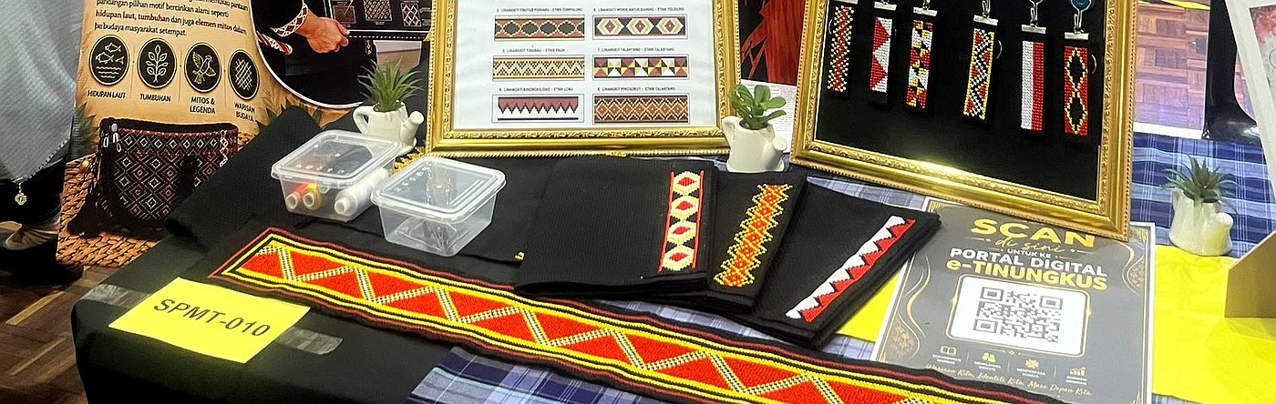 Kain sash panjang dengan motif merah dan kuning di atas meja